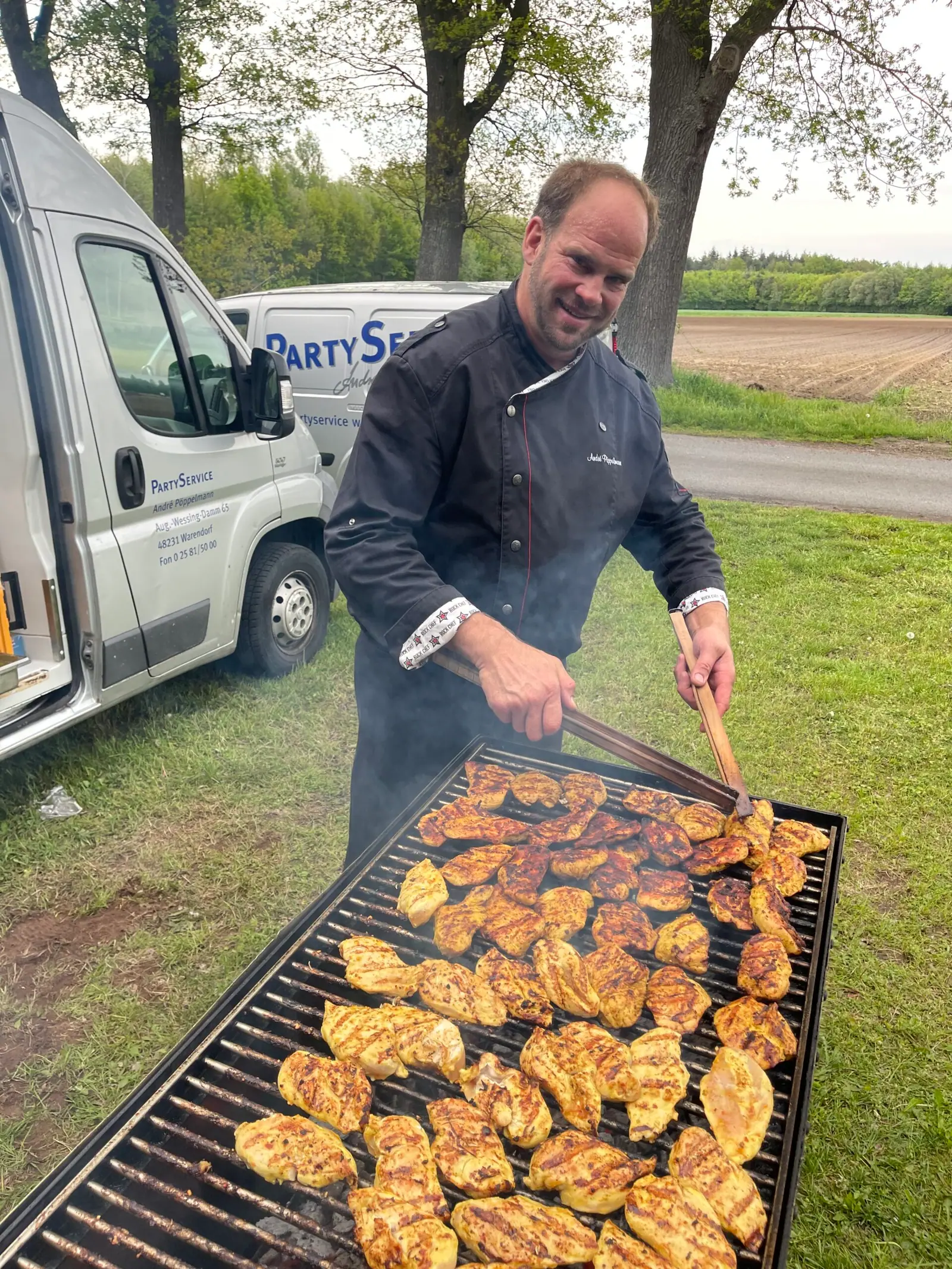 André Pöppelmann grillt Hähnchenbrustfilets bei einer Feier im Freien