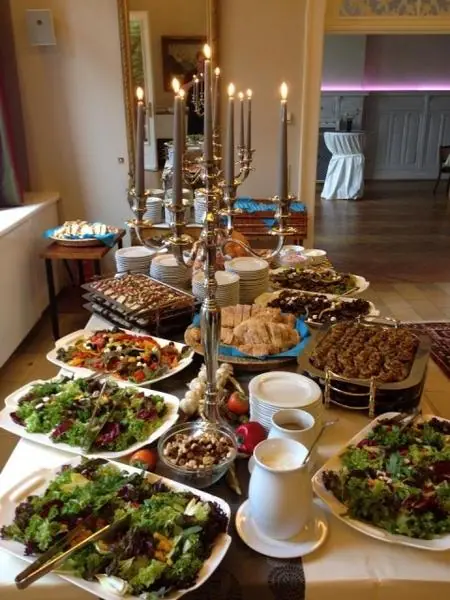 Buffet mit Salaten und Platten unter einem Kerzenleuchter