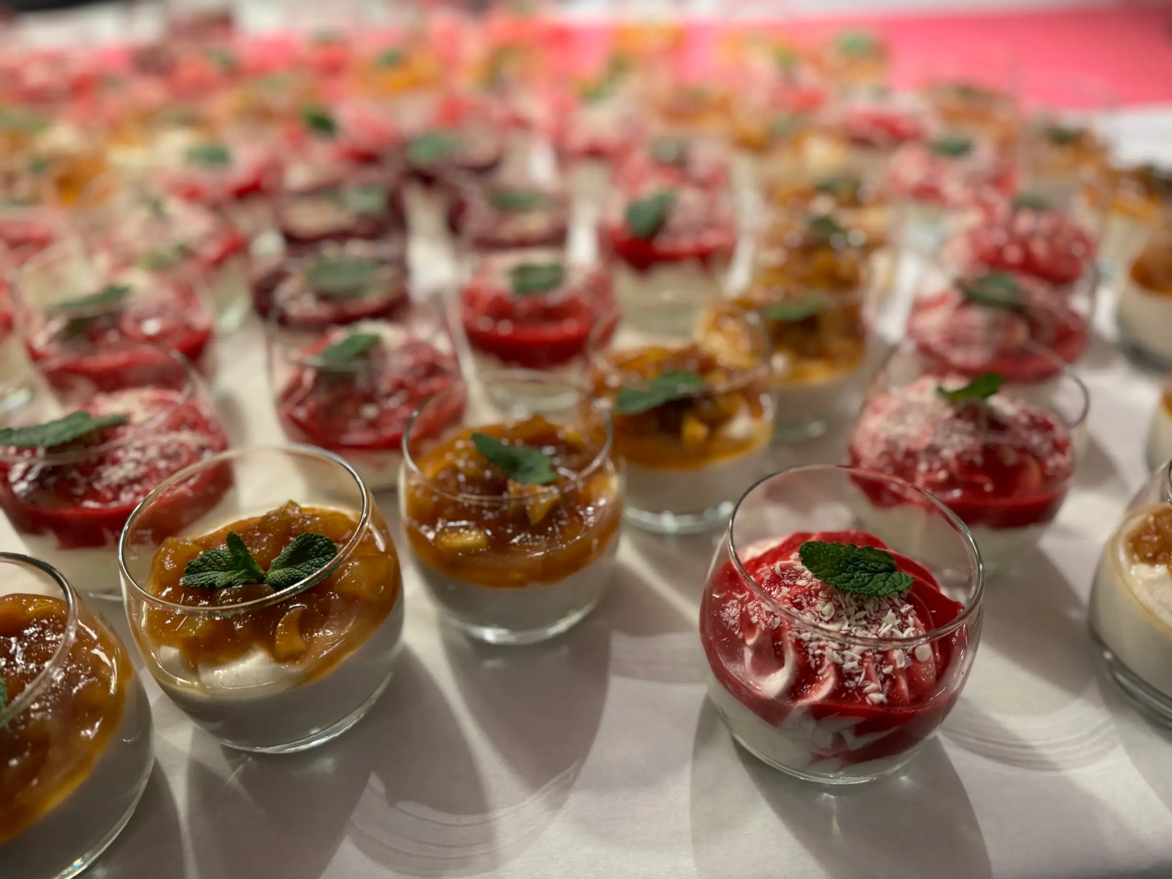 Desserts im Glas mit Beeren und frischer Minze, aufgereiht für ein Buffet