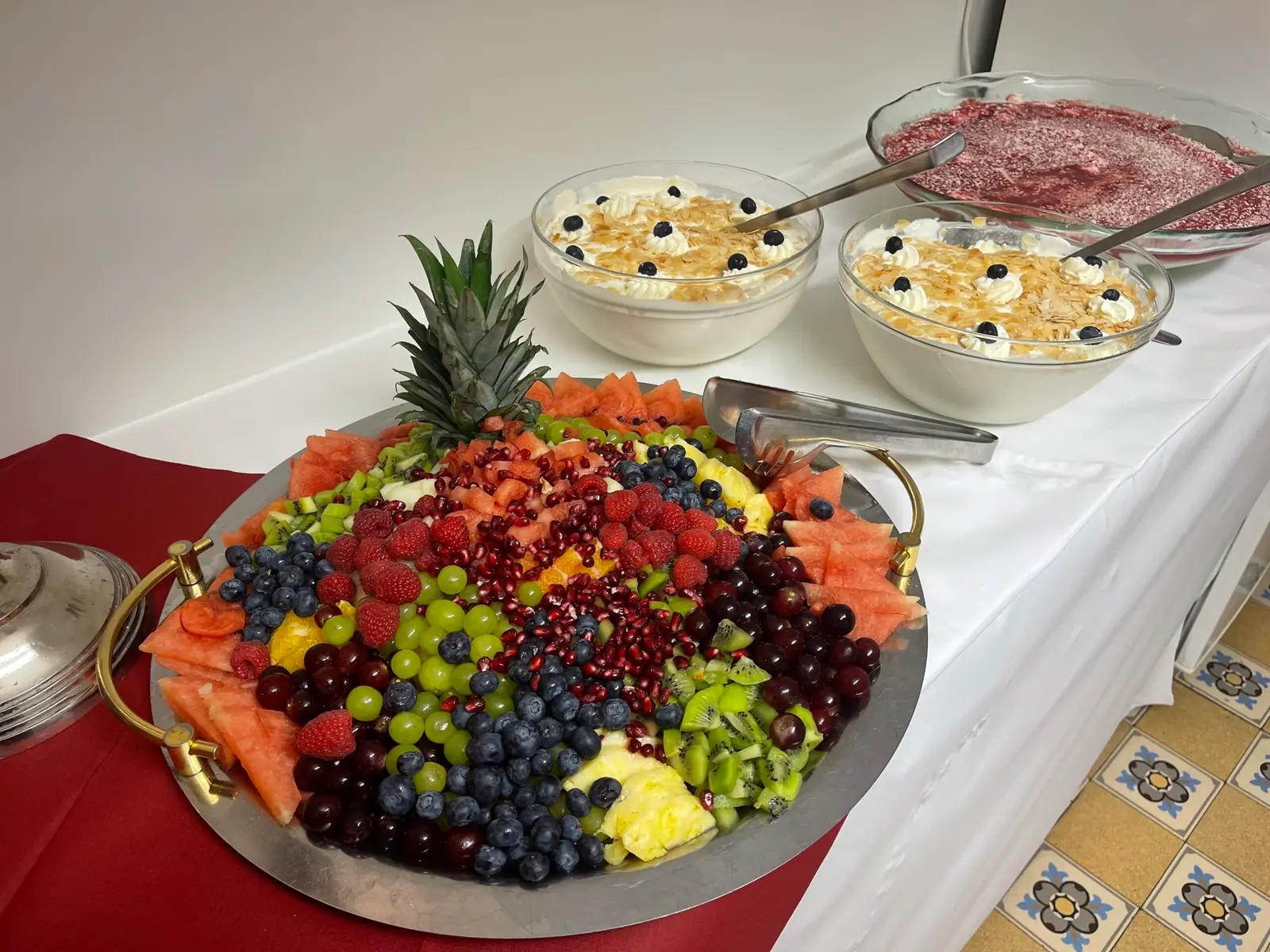Obstplatte mit Ananas, Trauben und Beeren neben Dessertschalen