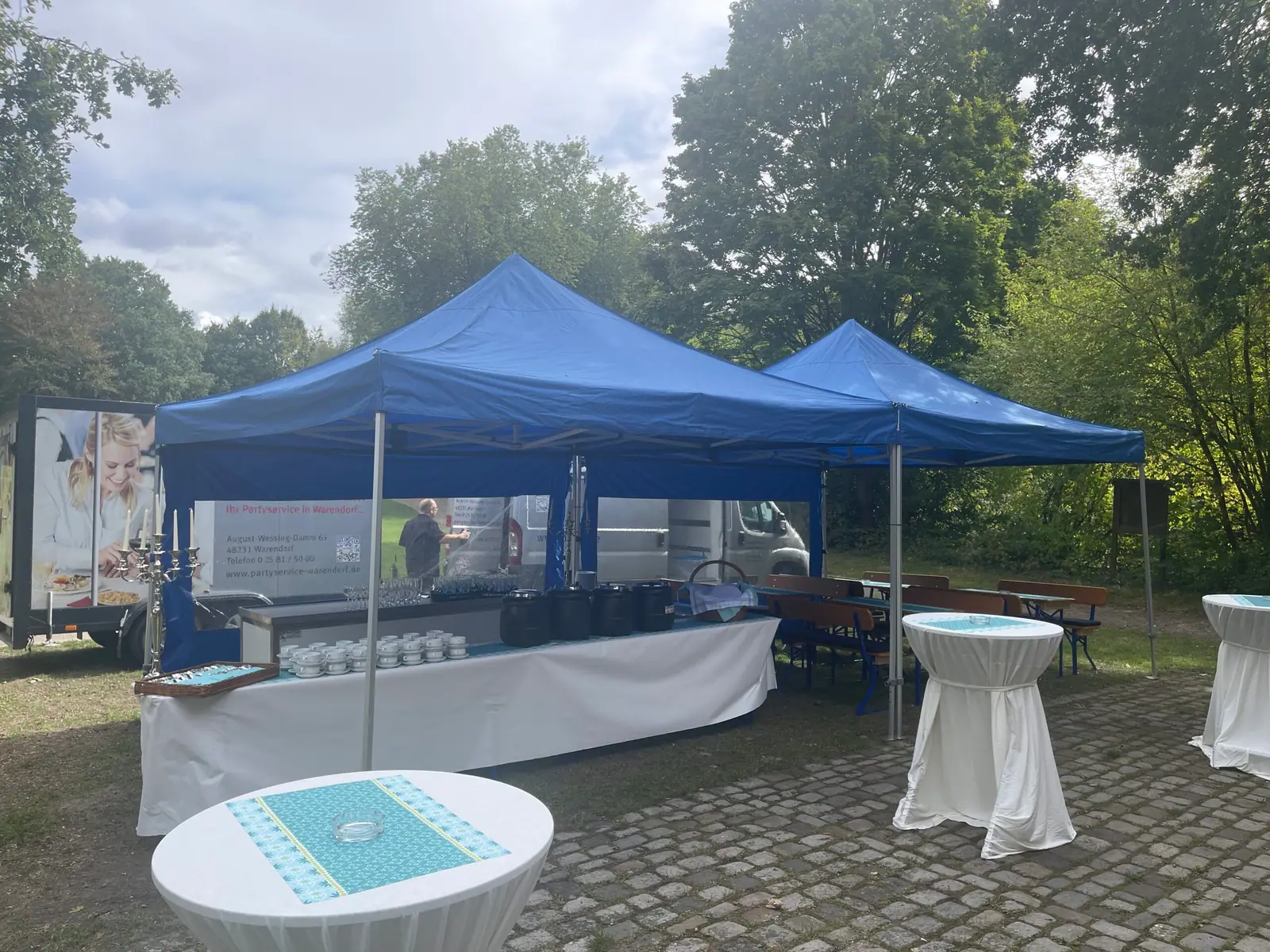 Blaue Pavillons, Buffettheke und Stehtische für eine Feier im Grünen